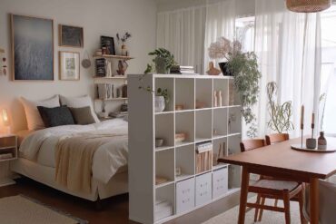 Kleines Wohnzimmer mit Regal als Raumtrenner zwischen Bett und Esstisch