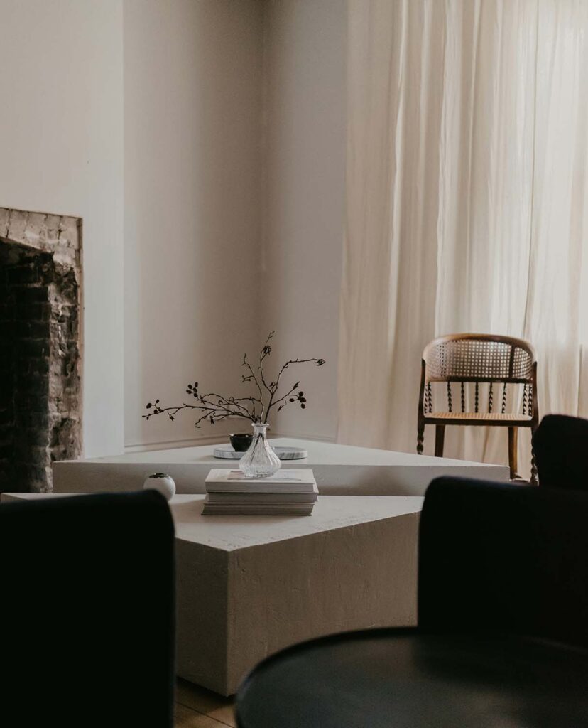 Minimalistisches Wohnzimmer mit schlichter Vase und Zweigen auf weißem Couchtisch