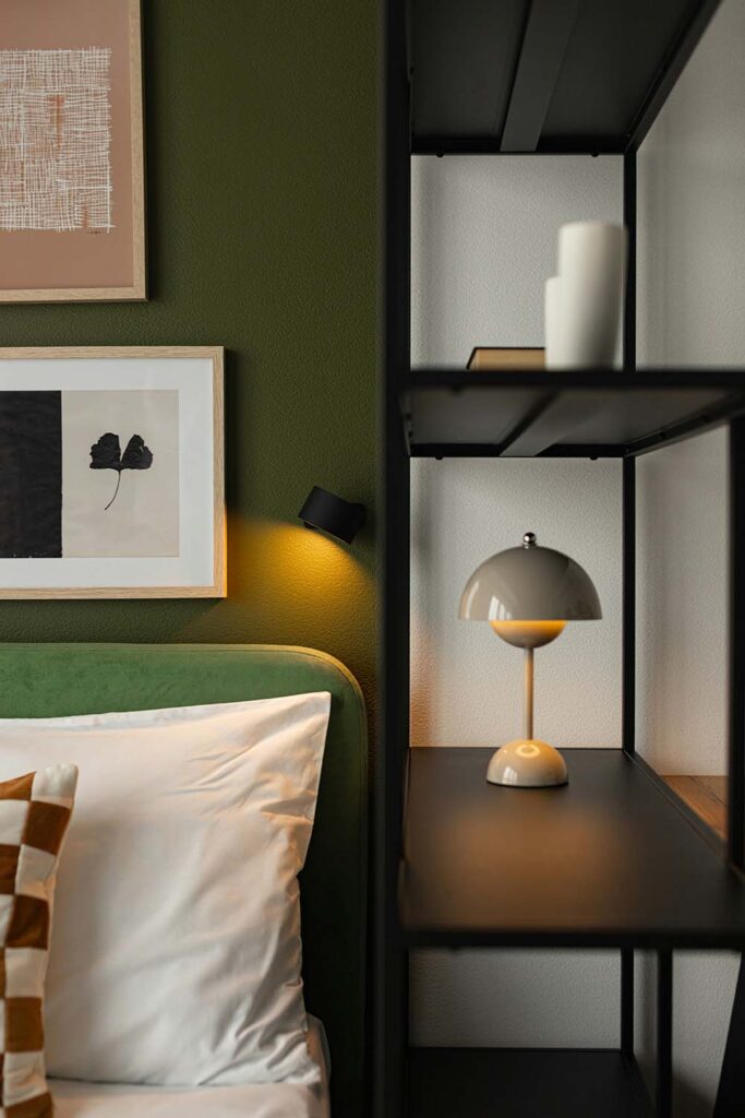 Detailaufnahme mit grüner Wand, Kunst an der Wand und Designlampe auf Regal