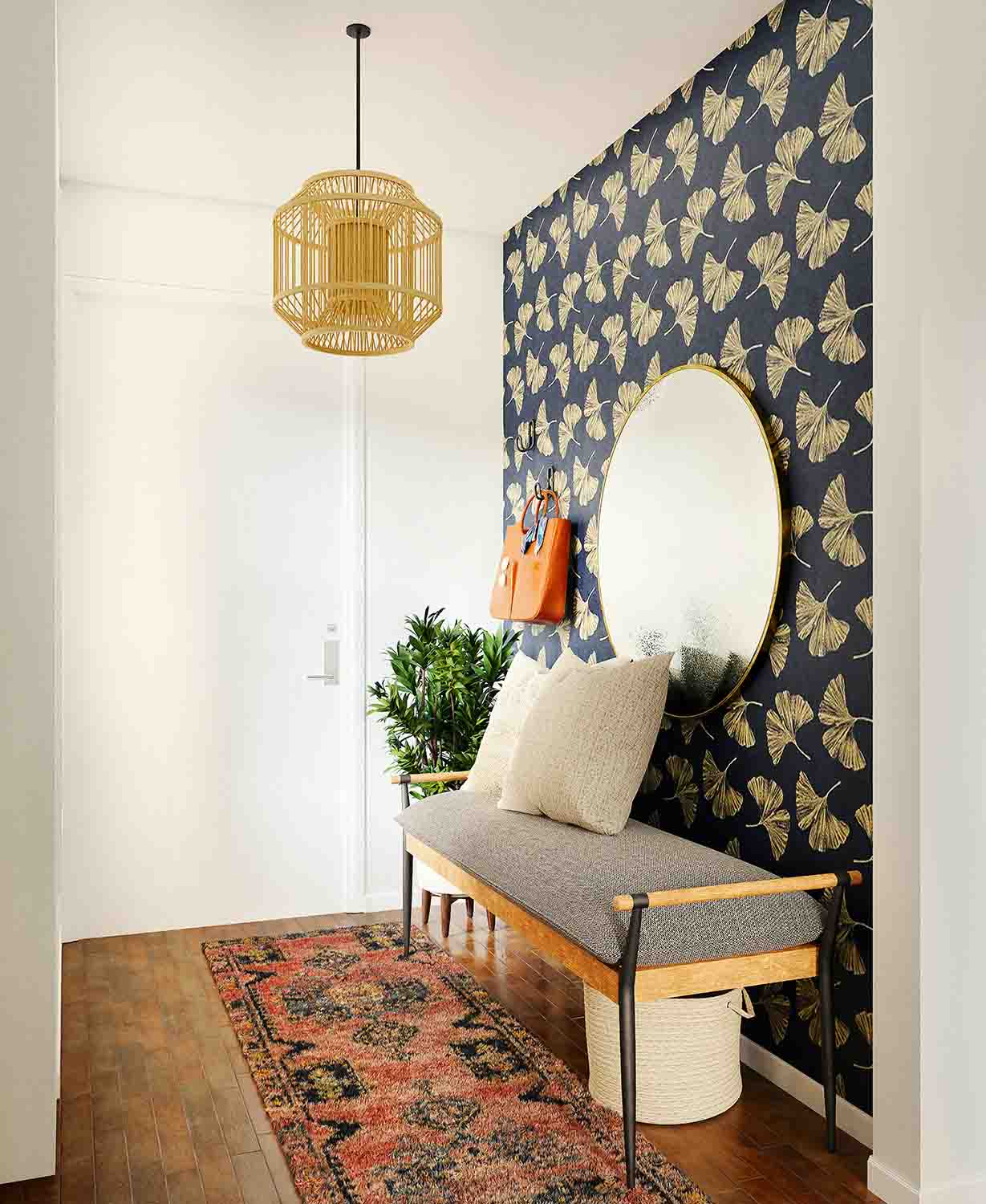 Stilvoller kleiner Flur mit gold-schwarzer Tapete, runder Spiegel und Sitzbank aus Holz