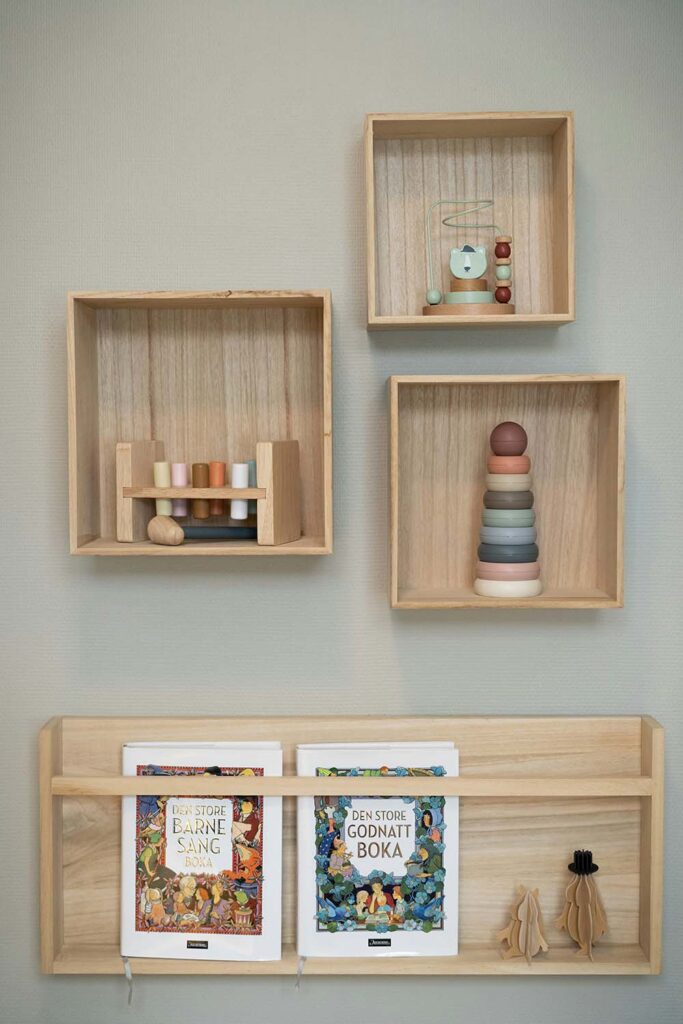 Holzregale mit Spielsachen und Büchern bringen natürliche Ordnung und Wärme ins Kinderzimmer.