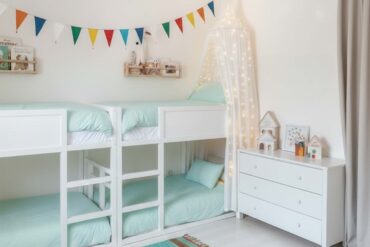 Zwei Etagenbetts mit jeweils zwei Schlafplätzen in einem hellen Kinderzimmer für Geschwister