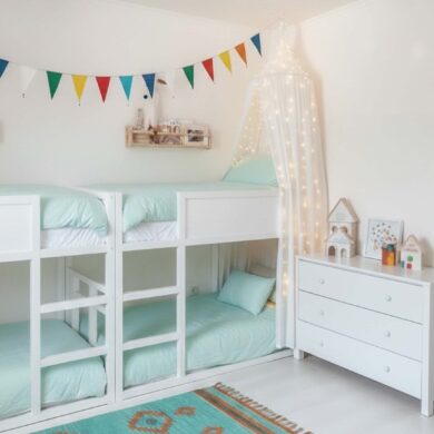 Zwei Etagenbetts mit jeweils zwei Schlafplätzen in einem hellen Kinderzimmer für Geschwister