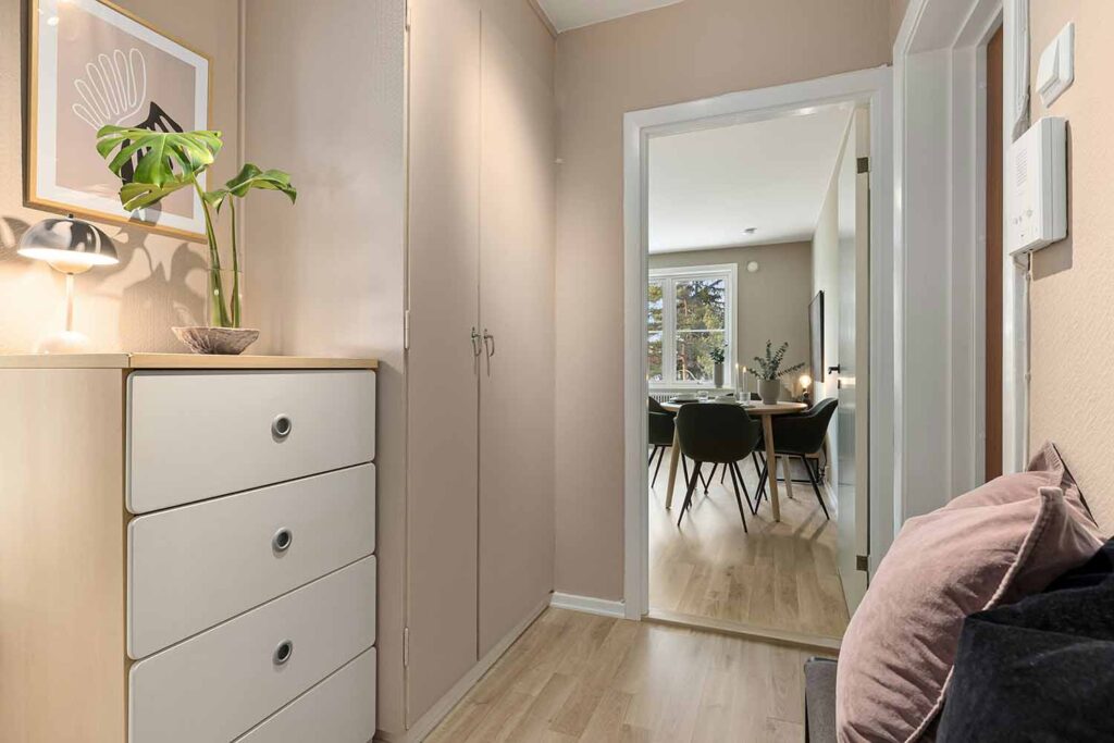 Wohnungsflur mit schmaler Kommode, Einbauschrank, Sitzkissen und Blick in den Essbereich