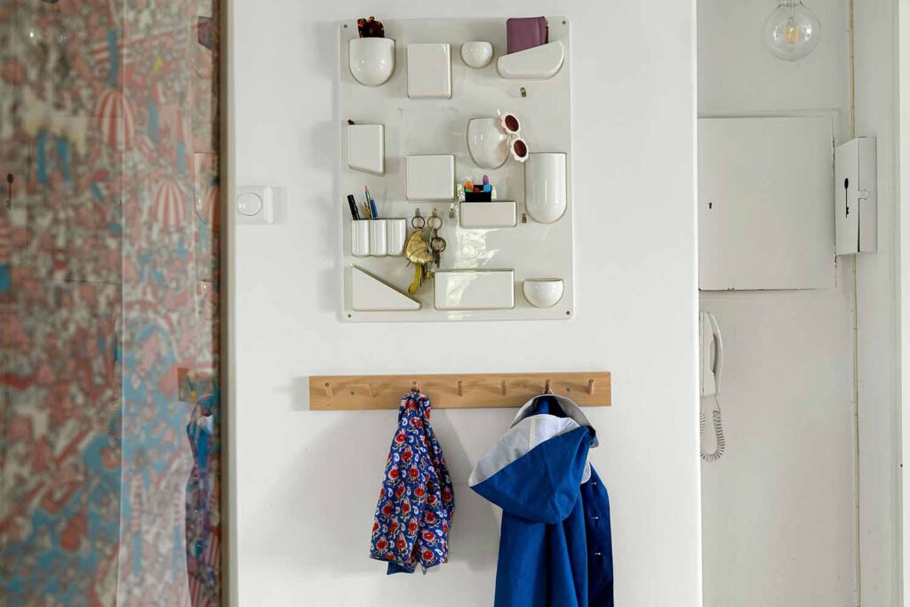 Wandorganizer im Flur mit Ablagefächern, Schlüsseln, Holzleiste mit Haken und Jacken an weißer Wand