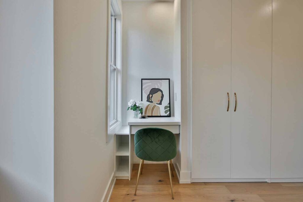 Schmaler Flur mit Arbeitsplatznische, kleinem Schreibtisch, Stuhl und deckenhohen Schränken