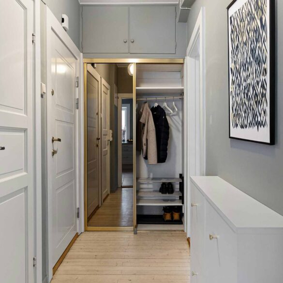 Schmaler Flur mit Einbau-Spiegelschrank, schmalem Schuhschrank, heller Wandfarbe und Holzboden