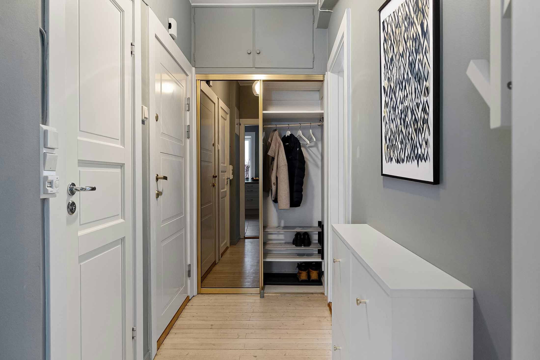 Schmaler Flur mit Einbau-Spiegelschrank, schmalem Schuhschrank, heller Wandfarbe und Holzboden