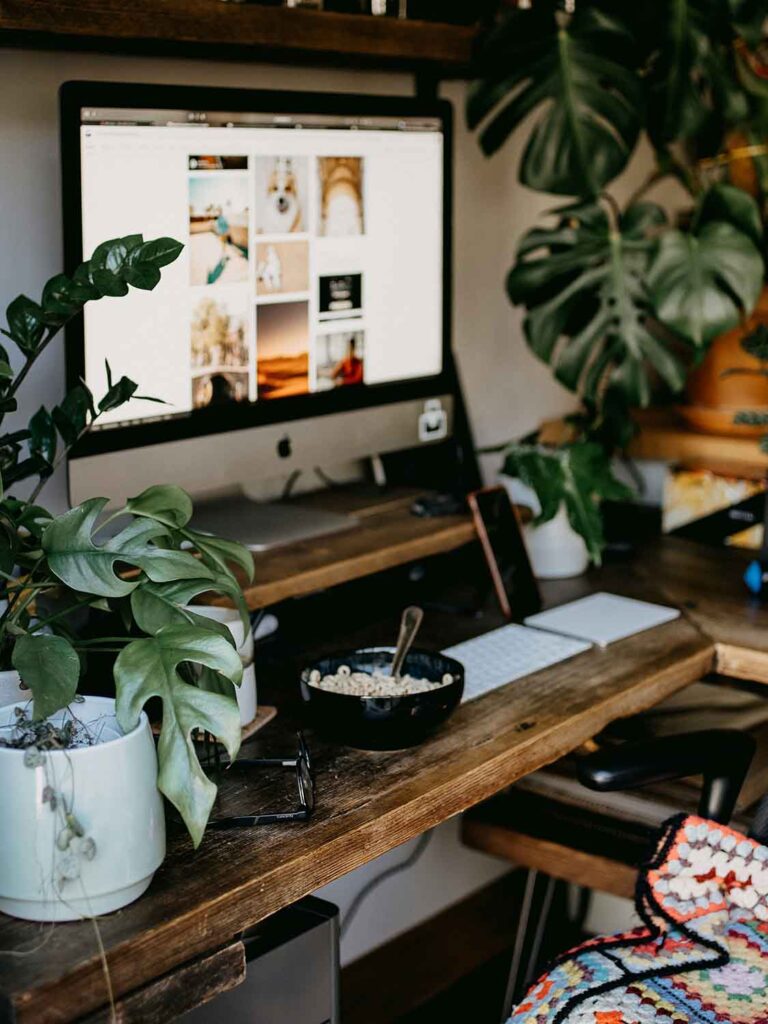 Arbeitsplatz im Schlafzimmer mit Holzschreibtisch, Desktop Monitor, Pflanzen auf dem Tisch und ruhiger Arbeitsatmosphäre