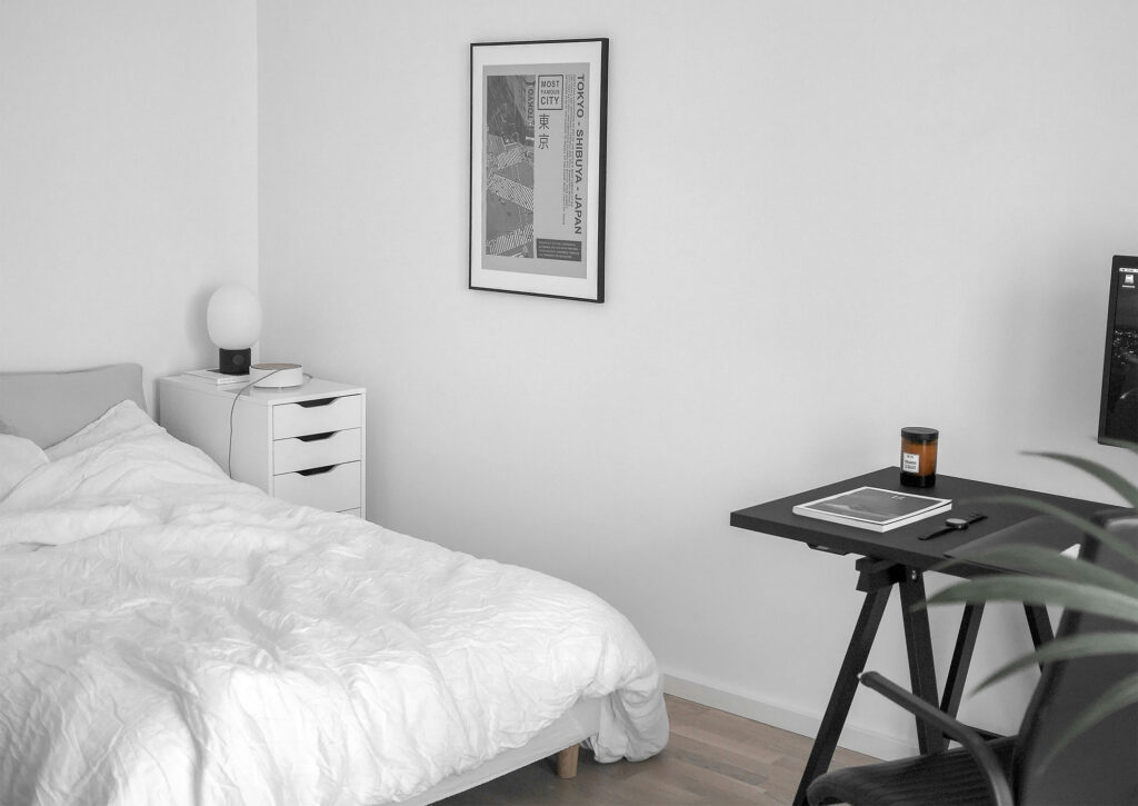 Minimalistisches Schlafzimmer mit schwarzem Schreibtisch an der Wand neben dem Bett und klarer Trennung von Schlaf- und Arbeitsbereich