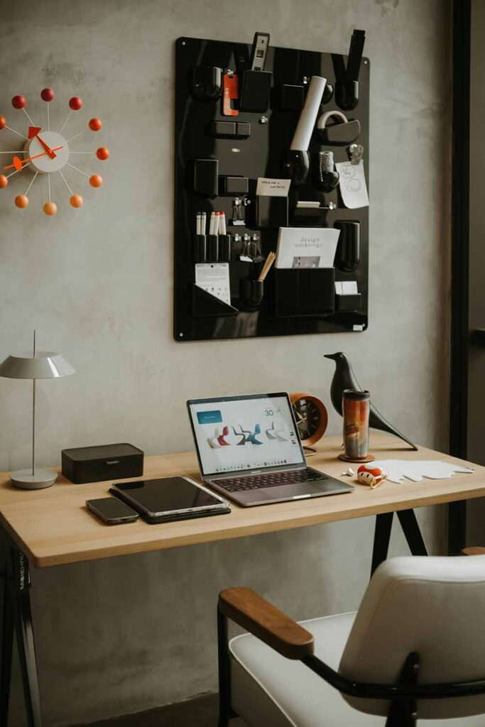 Arbeitsplatz im Schlafzimmer mit Wandorganisation, Laptop auf Holzschreibtisch und aufgeräumter Arbeitsfläche