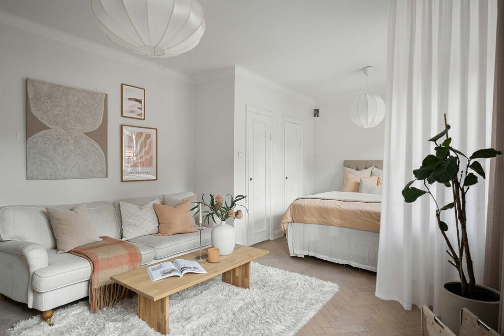 Heller Wohn Schlaf Bereich im Studio-Apartment mit Vorhang als sanfte Raumtrennung