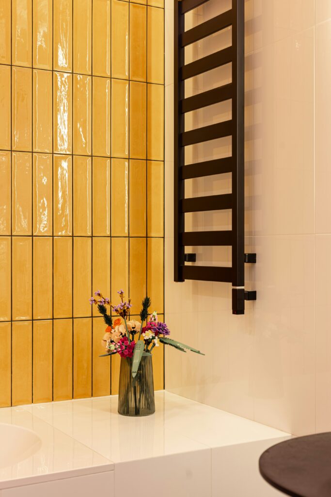 Kleines Bad mit gelben Fliesen und schwarzem Handtuchhalter