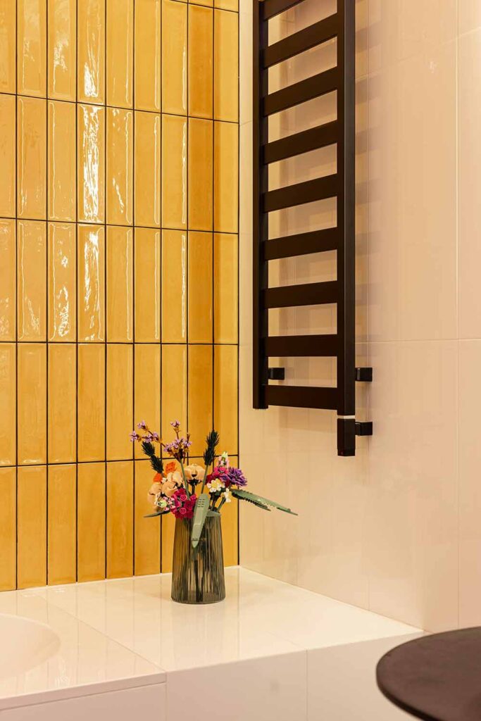 Kleines Bad mit gelben Fliesen und schwarzem Handtuchhalter