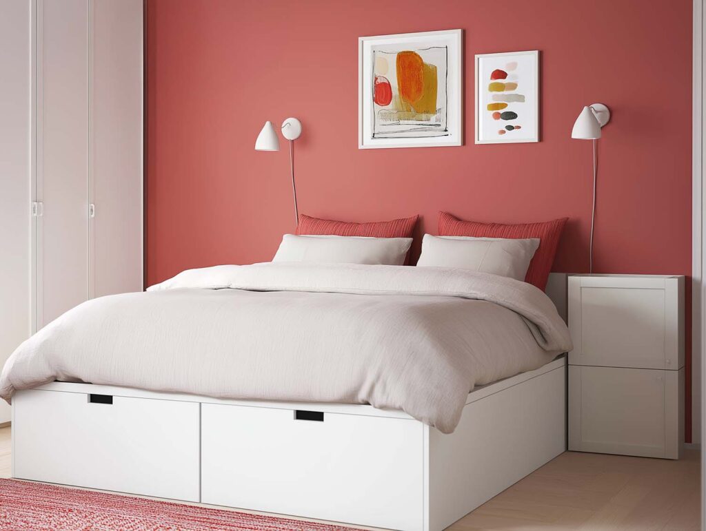 Weißes Bett mit großen Schubladen unter der Matratze vor roter Wand im modernen Schlafzimmer