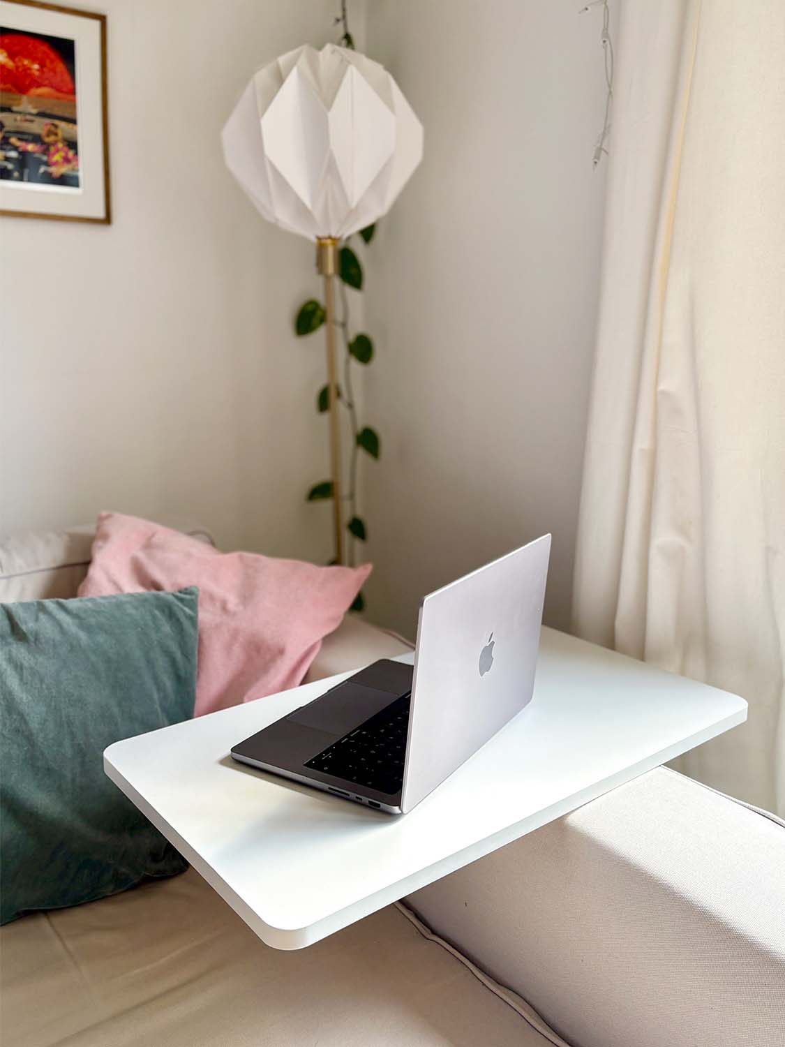 Kleiner weißer Schreibtisch in C-Form neben Sofa mit Laptop und Kissen im Wohnzimmer