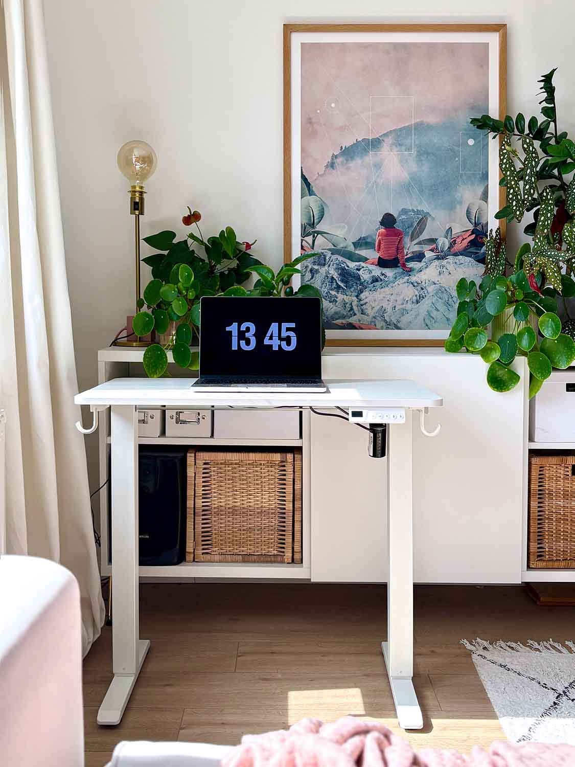 Kleiner weißer Schreibtisch mit zwei Beinen und Laptop vor Wandbild und Pflanzen