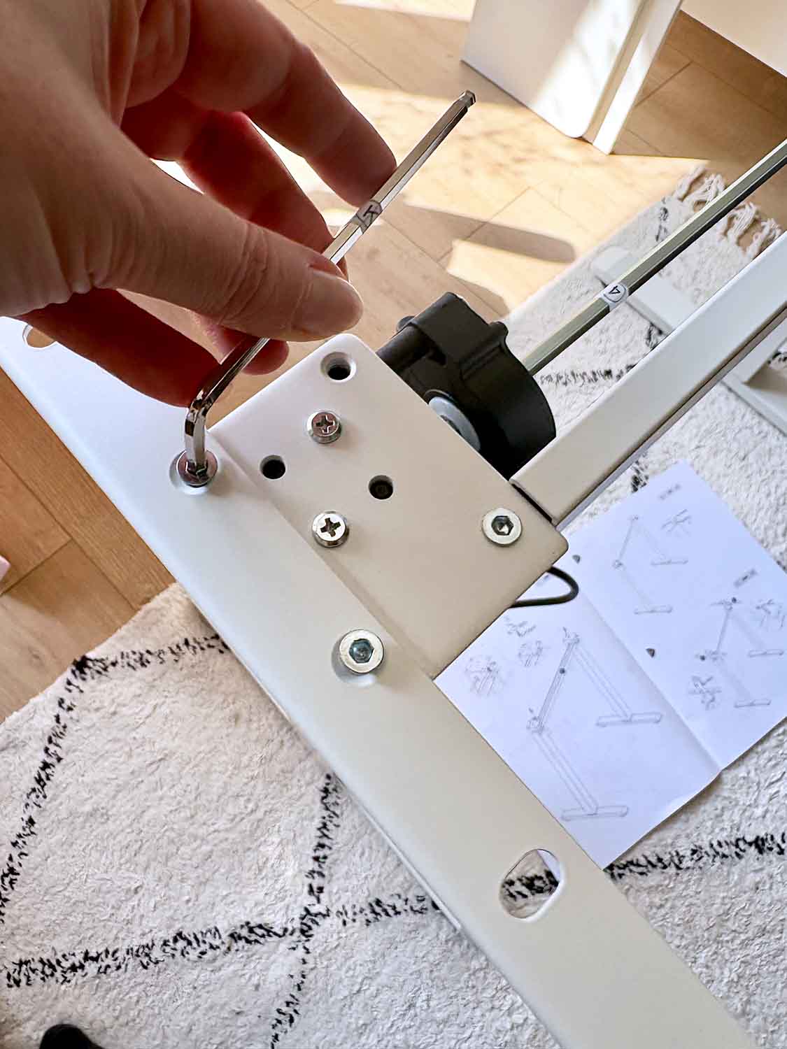 Hand montiert Schrauben an Metallteil eines höhenverstellbaren Schreibtischgestells